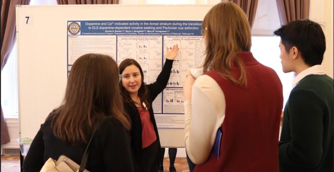 A woman presenting a research poster to three people